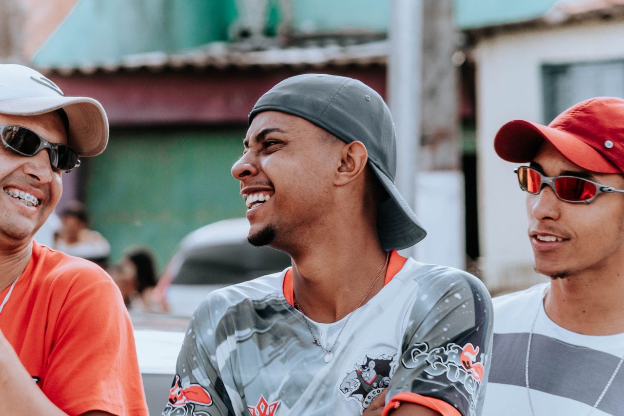 Three men in casual attire share a laugh outdoors, creating a vibrant and lively scene.
